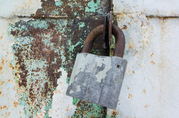 Old rusted padlock hanging on metal door
