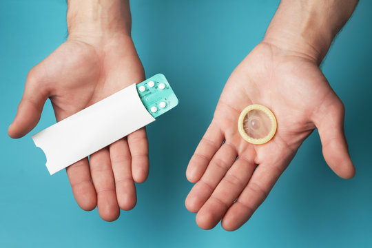 Male contraceptives. Pills and condom in hands of men