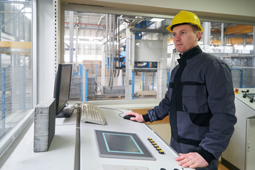 Engineer worker at control room. Portrait of a young technician worker in a factory. The operator monitors the work process from control room