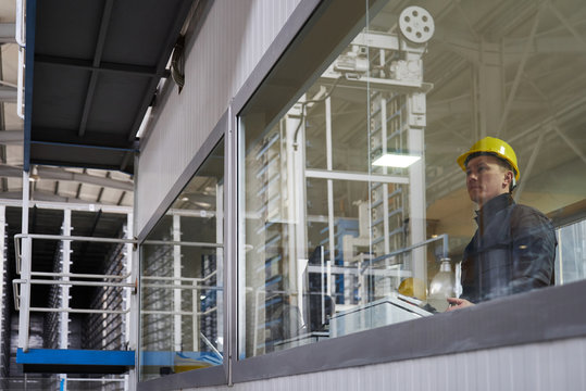 Engineer worker at control room. Portrait of a young technician worker in a factory. The operator monitors the work process from control room