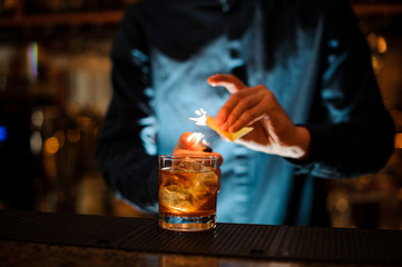 Brunet bartender serving a fresh alcoholic cocktail with a smoky note