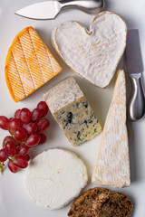 French cheeses plate in assortment, blue cheese, brie, munster, soft goat cheese, Neufchatel heart shaped cheese top view © barmalini