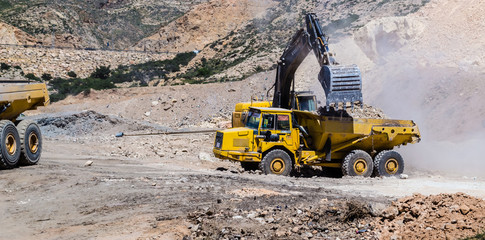 Wheel loader Excavator unloading sand with water during earth moving works at construction site