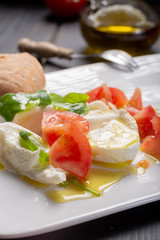 Caprese salad with tomatoes, basil,  mozzarella balls, made with white ball mozzarella buffalo Italian soft cheese and olive oil