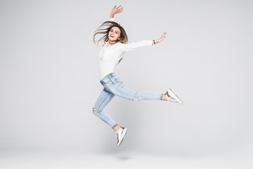 Full length portrait of a cheerful woman jumping isolated on a white background
