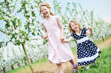 Fototapeta premium Two little girl run and having fun in spring garden