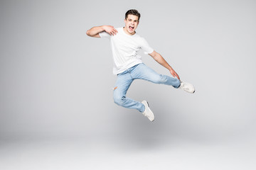 Cheerful young man jumping over white background