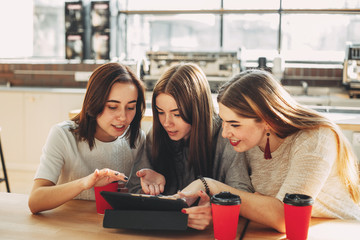Three women discussing online content at a tablet.