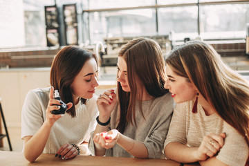 Three young women friends smelling new perfume