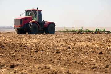 Obraz premium Farmer in tractor preparing land with seedbed cultivator