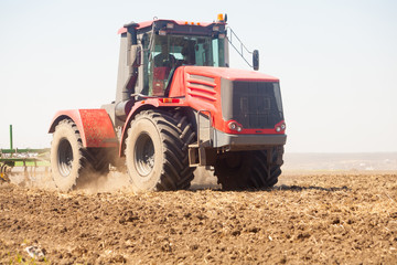 Fototapeta premium Farmer in tractor preparing land with seedbed cultivator