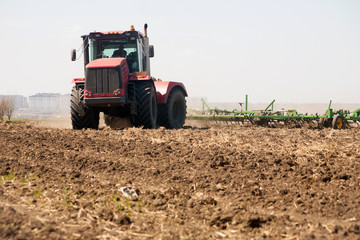 Fototapeta premium Farmer in tractor preparing land with seedbed cultivator