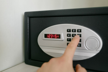 easy password. Hand press key on black safety box in hotel room. Concept safe storage of money and documents