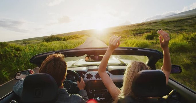 Couple driving into the sunset in convertible, slow motion