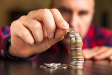 Man counts his coins on a table. Personal finance, finance management, thrifty or avarice concept.