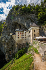 Fototapeta premium Renaissance Castle Built Inside Rocky Mountain in Predjama, Slovenia. Famous Tourist Place in Europe.
