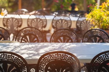 The free space in the outdoor restaurant. Not covered with large tables in the cafe on the street. Metal chairs with a Greek pattern.