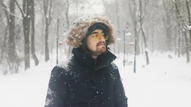 calm thoughtful young man enjoying winter snowy weather in beautiful snowy park smile stylish look hipster style businessman traveling walking outdoors pensive satisfied face peace of mind portrait