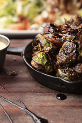 Brussel Sprouts roasted in an iron pan accompanied by a butter dressing on the side