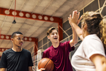 Obraz premium Group of teenager friends on a basketball court giving each other a high five