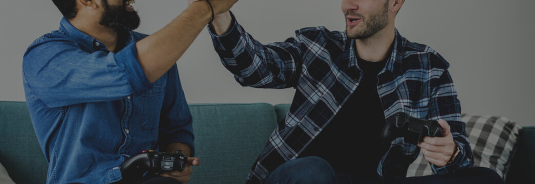 Men playing video game on sofa giving each other a high five leisure and teamwork concept