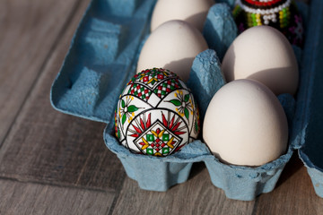 white organic eggs in tray and traditional painted easter eggs from Bucovina region, Romania