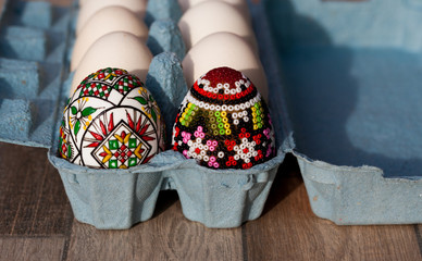 white organic eggs in tray and traditional painted easter eggs from Bucovina region, Romania