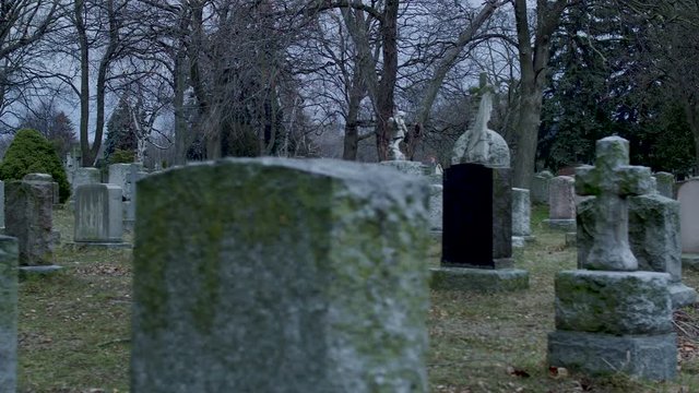 We are in a graveyard moving slowly across the moss covered tombstones. Evening.