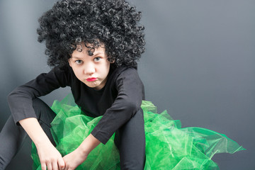 Sad girl in a black curly wig and a dance suit