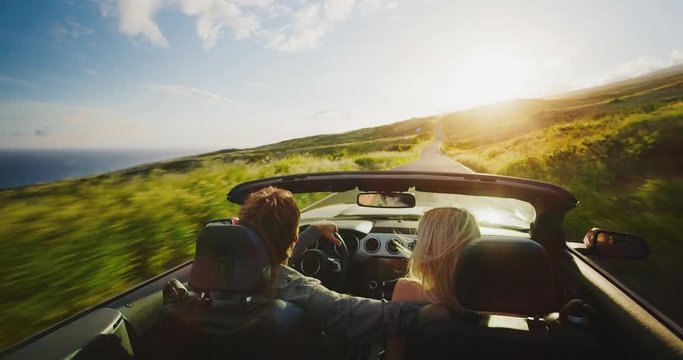 Couple driving into the sunset in convertible