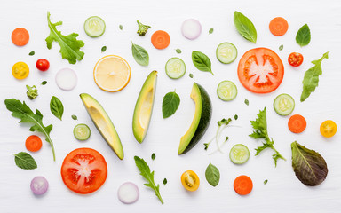 Food pattern with raw ingredients of salad. Various vegetables lettuce leaves, cucumbers, tomatoes, carrots, broccoli, basil ,onion and lemon flat lay on white wooden background.