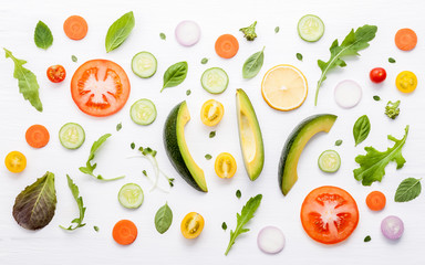 Food pattern with raw ingredients of salad, lettuce leaves, cucumbers, tomatoes, carrots, broccoli, basil ,onion and lemon flat lay on white wooden background.