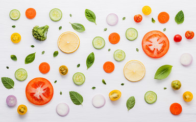 Food pattern with raw ingredients of salad, lettuce leaves, cucumbers, tomatoes, carrots, broccoli, basil ,onion and lemon flat lay on white wooden background.