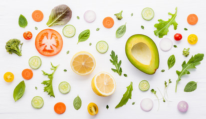 Food pattern with raw ingredients of salad, lettuce leaves, cucumbers, tomatoes, carrots, broccoli, basil ,onion and lemon flat lay on white wooden background.
