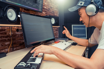 asian musical producer arranging a song on digital recording equipment in home studio