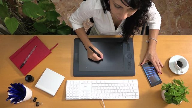 Female designer sketching furniture using graphic tablet and smartphone. Caucasian woman drawing interior design project with computer at office. Architect at work, creative job and technology