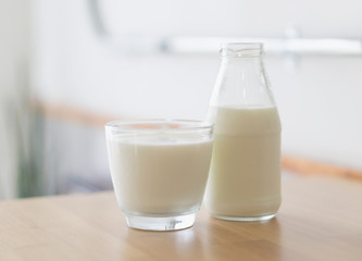 Closeup glass and bottle of millk on wood table background for healthy drink concept, selective and soft focus