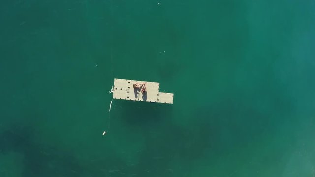 Aerial of two girls tanning on a floating platform