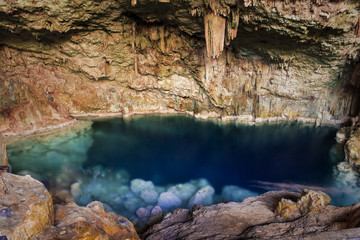 beautiful natural pool of crystal clear water formed in a rocky cave with stalagmites and stalagmites