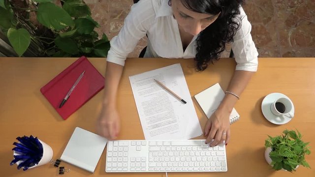 Active businesswoman proofreading draft text on computer and making paper ball. Caucasian woman typing on keyboard marking correction and wresting crumpled sheet in trash basket. Editing and revision