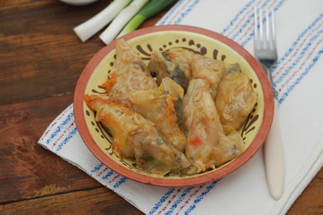 Stuffed Rolled Cabbage meat in Leaves in a Ceramic Plate with White Napkin,Parsley on a Rustic Wooden background. Traditional Romanian Russian Ukrainean Food.