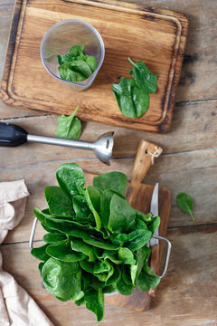 Top view fresh bunch of spinach leaves with blender for cooking sauce on wooden table