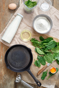 Top view set of ingredients for cooking spinach pancakes on wooden table. Healthy spinach pancakes. Recipe for spinach pancakes