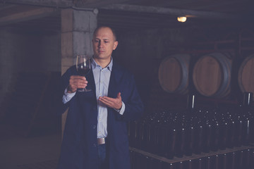Wine producer inspecting red wine in cellar