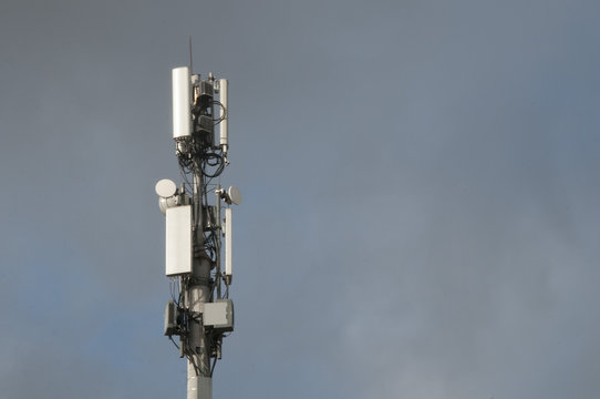 Cell tower closeup against a white sky.