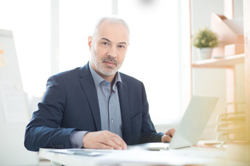 Portrait of businessman sitting at the table and working on laptop at office