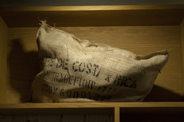 Stack of coffee bean-guny sacks on ceiling shelf in warehouse .