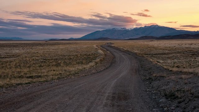Time lapse over winding road during colorful sunrise in the West Desert in Utah.
