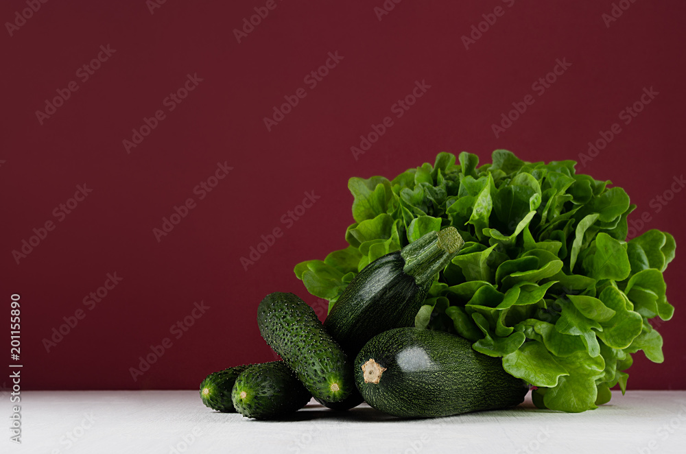 Wall mural Green summer vegetables on white wood board and bordo kitchen wall. Modern elegant colorful concept kitchen interior.