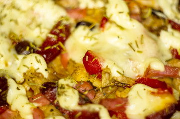 homemade pizza with peppers, plums, ham, sausage, cheese and spices, closeup